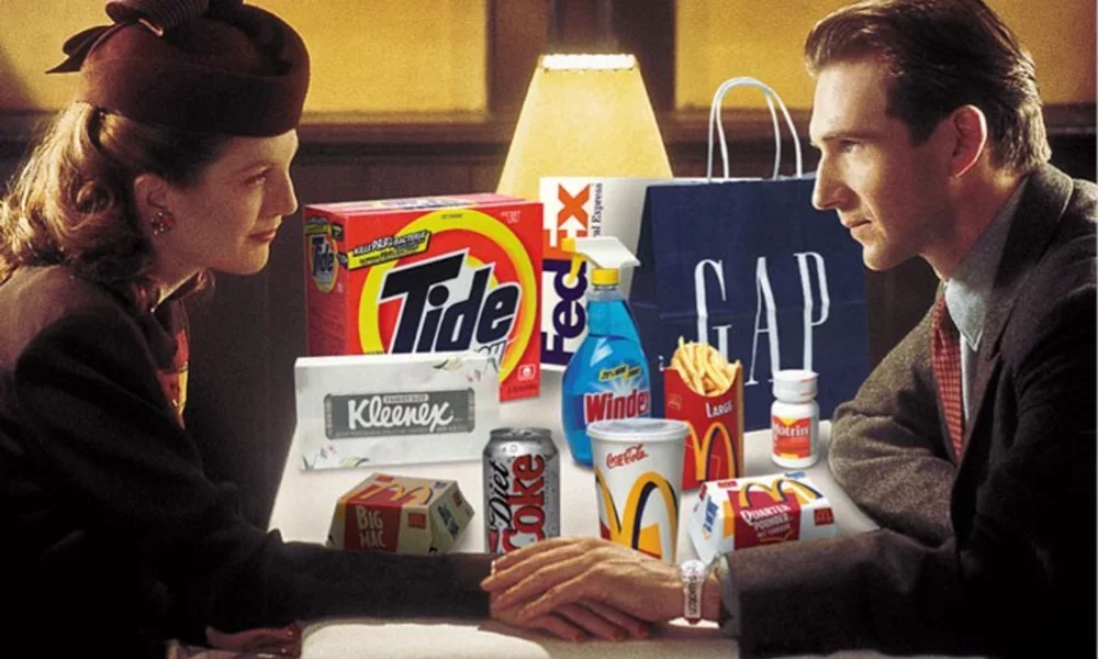 A woman and a man sit across from each other at a table with various fast food items and cleaning products, holding hands.