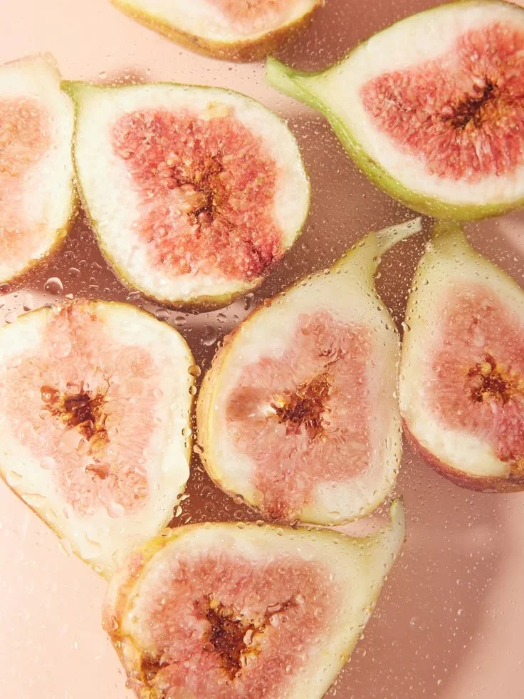 Close-up of halved fresh figs submerged in water with bubbles.