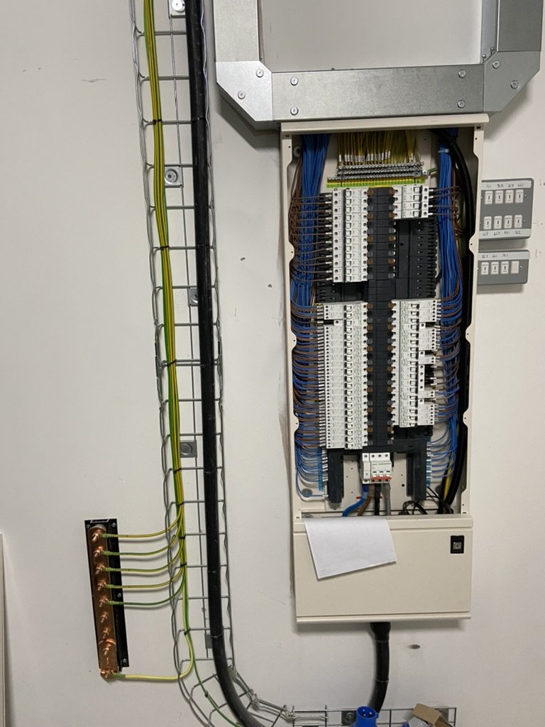 Electrical wiring panel with various colored wires, circuit breakers, and electrical components.