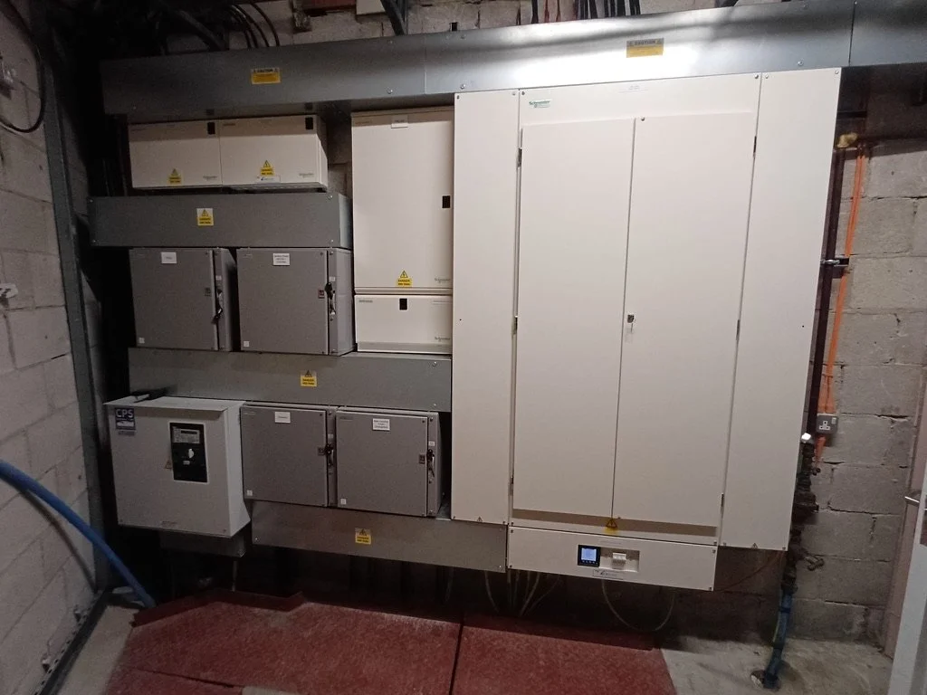 Electrical panels and circuit breaker boxes installed on a concrete wall in an industrial or utility room.