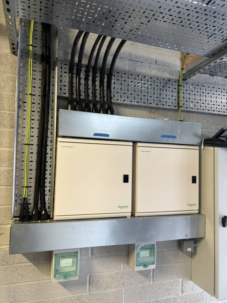 Electrical control panel with Schneider Electric components mounted on a wall, with digital meters below.