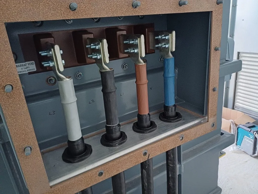 Inside an electrical panel showing four colored wires connected to circuit breakers or terminals.