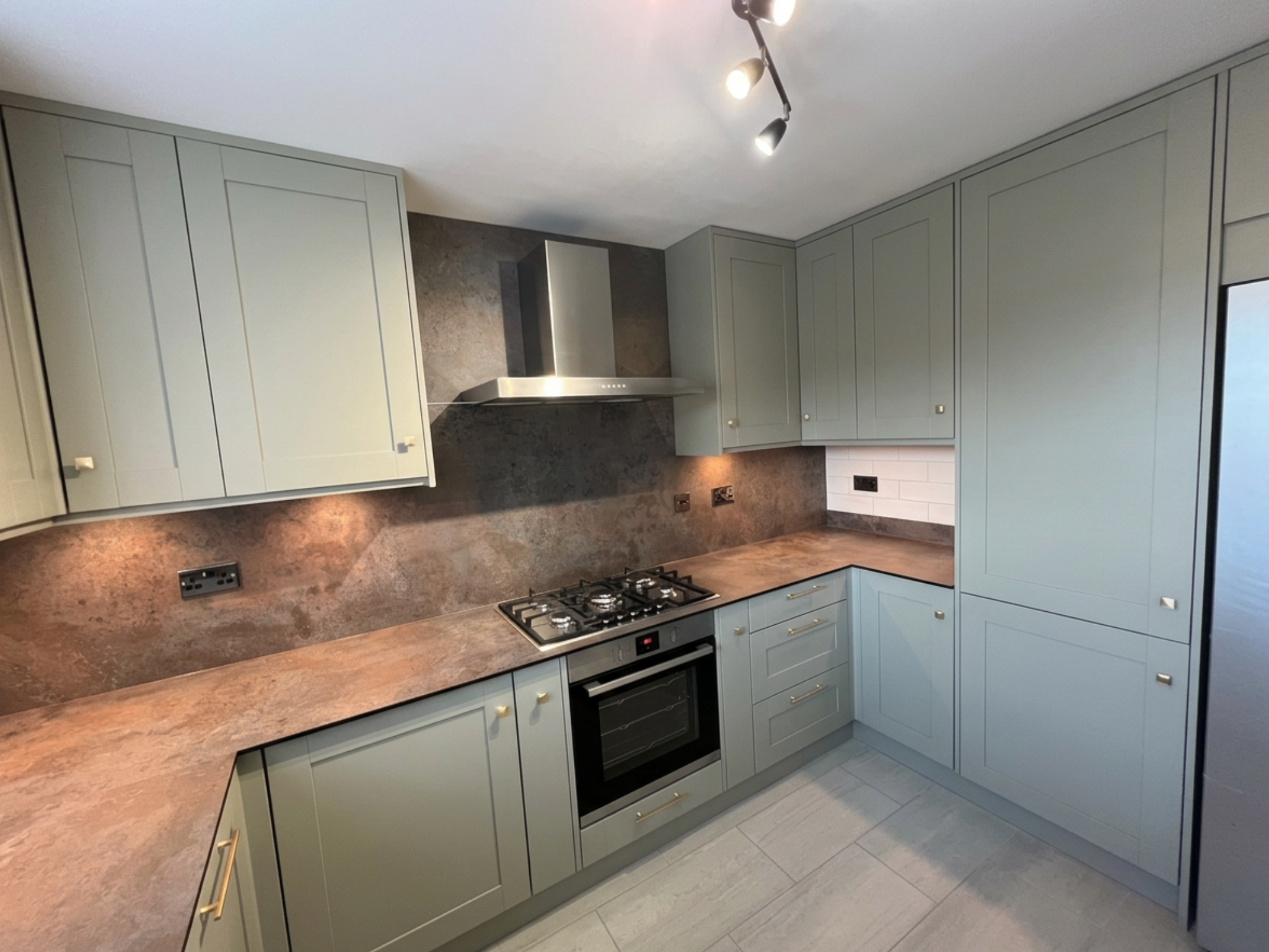 Professionally installed L-shaped kitchen featuring sage green shaker-style cabinetry.