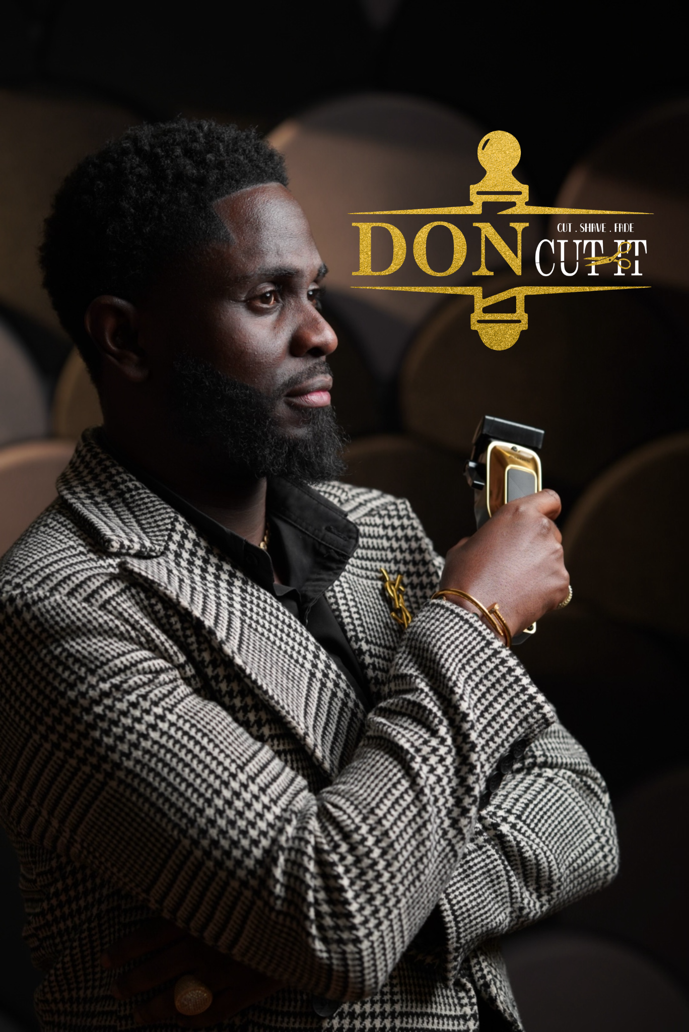 A man with dark skin, textured short hairstyle, and a beard, wearing a houndstooth patterned blazer and gold jewelry, holding a gold and black vintage-style device, sitting indoors with brown cushioned seats in the background, with a graphic overlay reading 'DON CUT' and additional text 'CUT, SHAVE, FADE'.