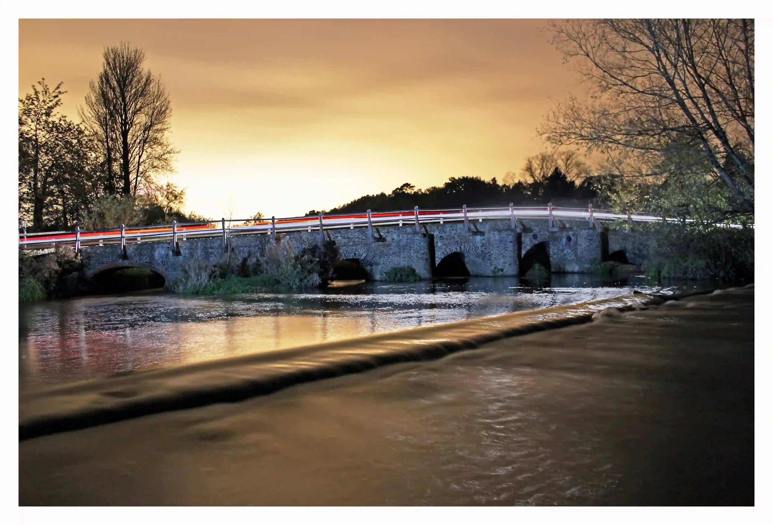 TILFORD BRIDGE AT NIGHT
Tilford Bridge, Tilford, Surrey, Uk. 
A medieval bridge with such proud character across the river Wey on this damp cloudy night.  Illuminated by urban lights made the sky look like a golden blanket as the bridge, that has und