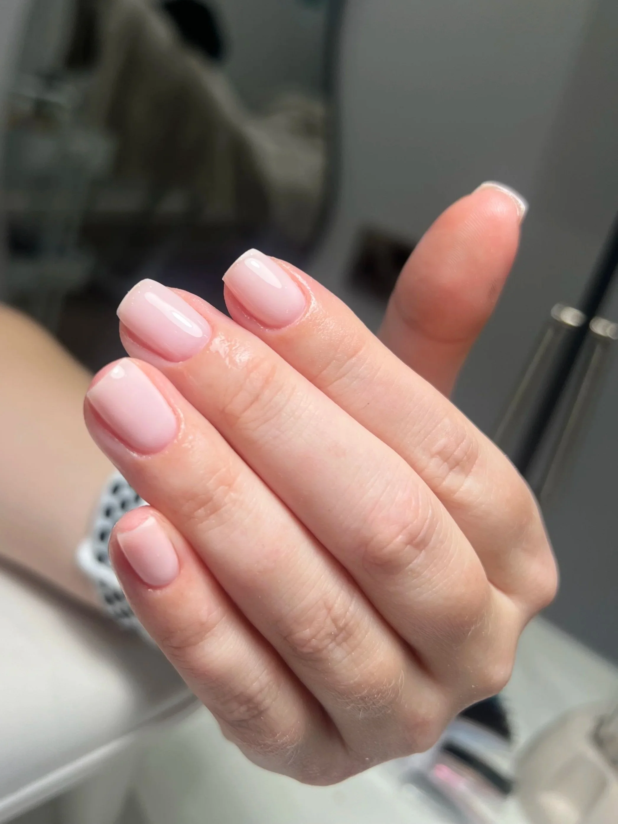 Close-up of a person's hand with well-manicured, shiny, French-style nails.