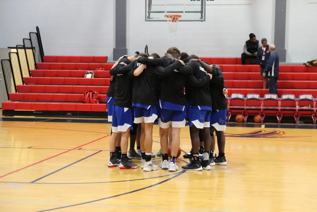 Basketball team huddled together on a court for a team meeting or pep talk.