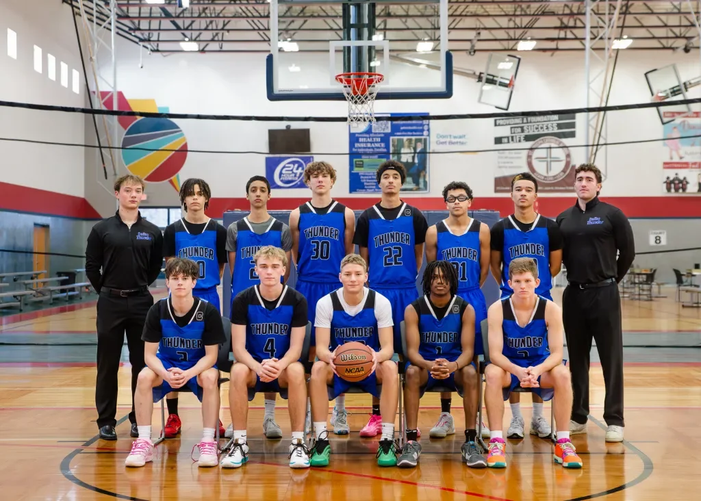 A youth basketball team called the Thunder, with players and coaches, in a gymnasium for a team photo.