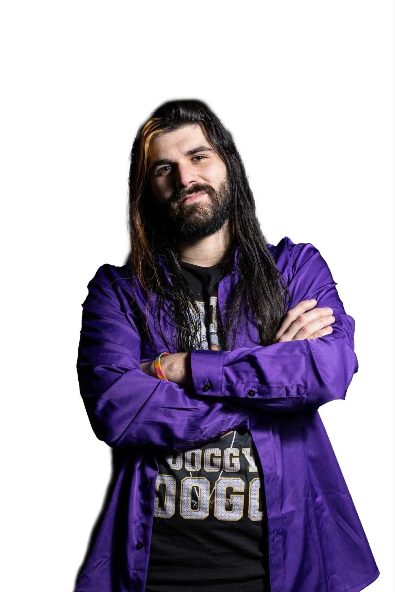 A man with long black hair, a beard, and crossed arms wearing a purple jacket and a black shirt with gold lettering against a white background.