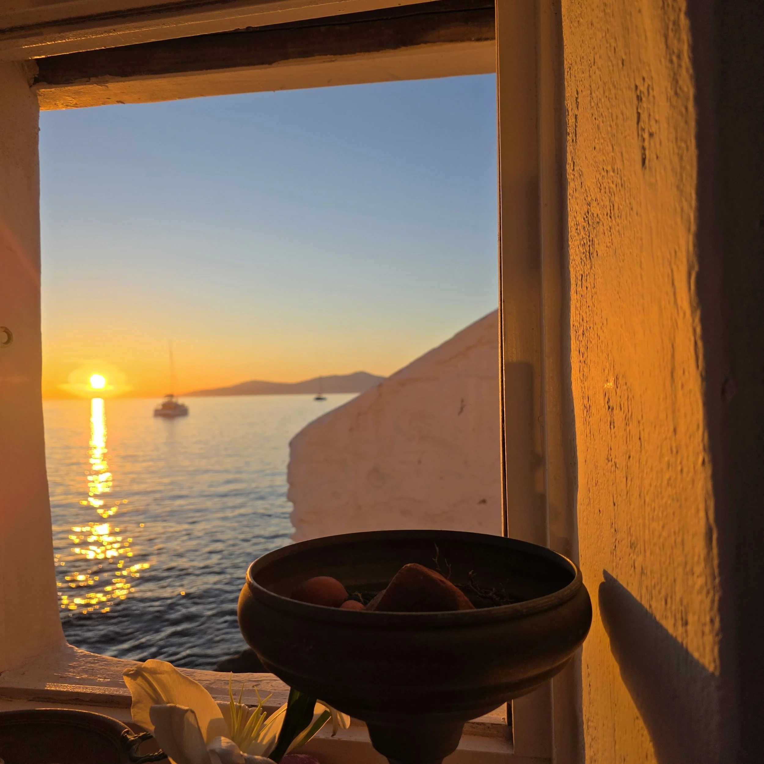 Sunset view over the sea through a window at Kastro's restaurant in Mykonos, Greece.