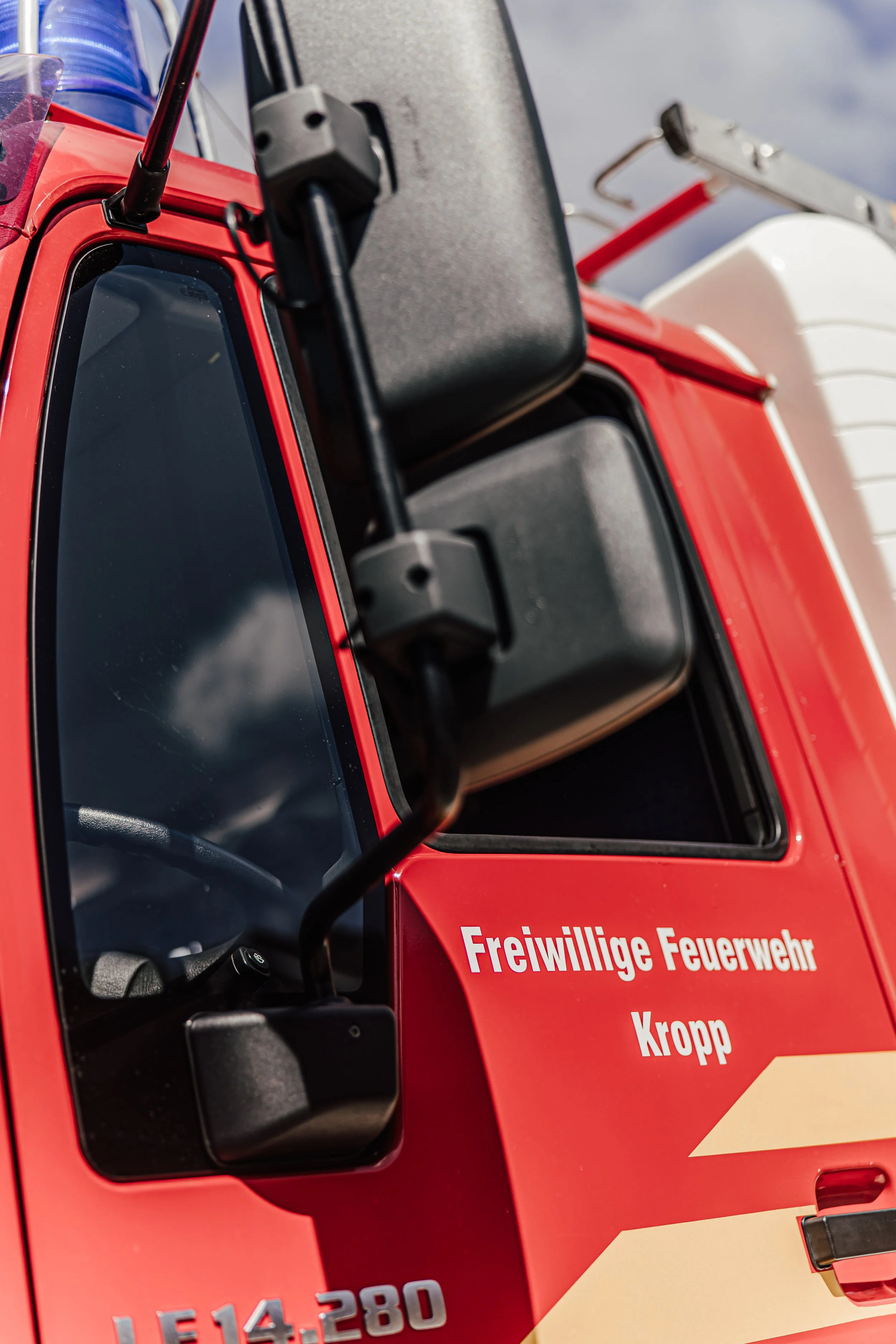 Nahaufnahme eines Feuerwehrfahrzeugs mit deutschem Schriftzug 'Freiwillige Feuerwehr'.