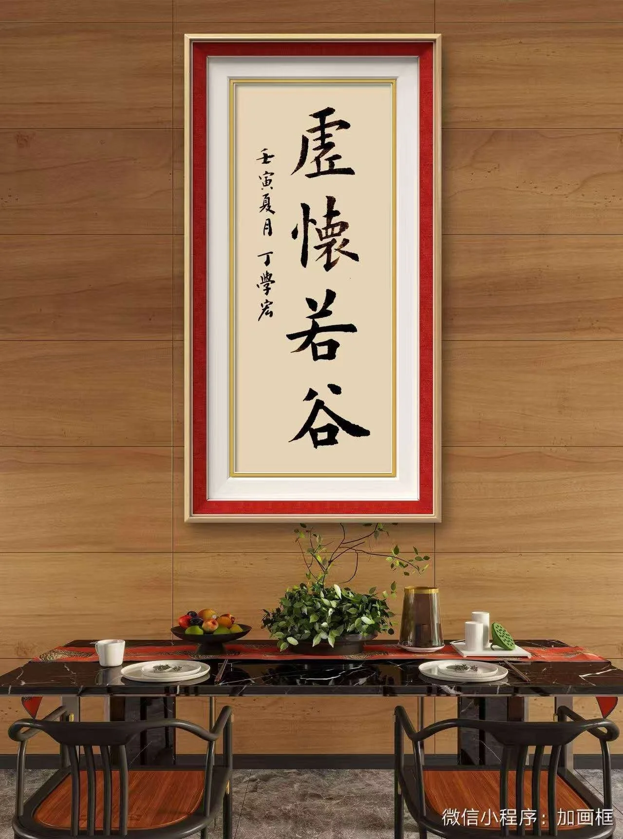 A dining table set against a wooden wall, with a large framed piece of Chinese calligraphy hanging above it. The table has a black marble top, with a bowl of fruit, a potted plant, a brass vase, cups, plates, and a green item on a tray. Four chairs with wooden seats surround the table.