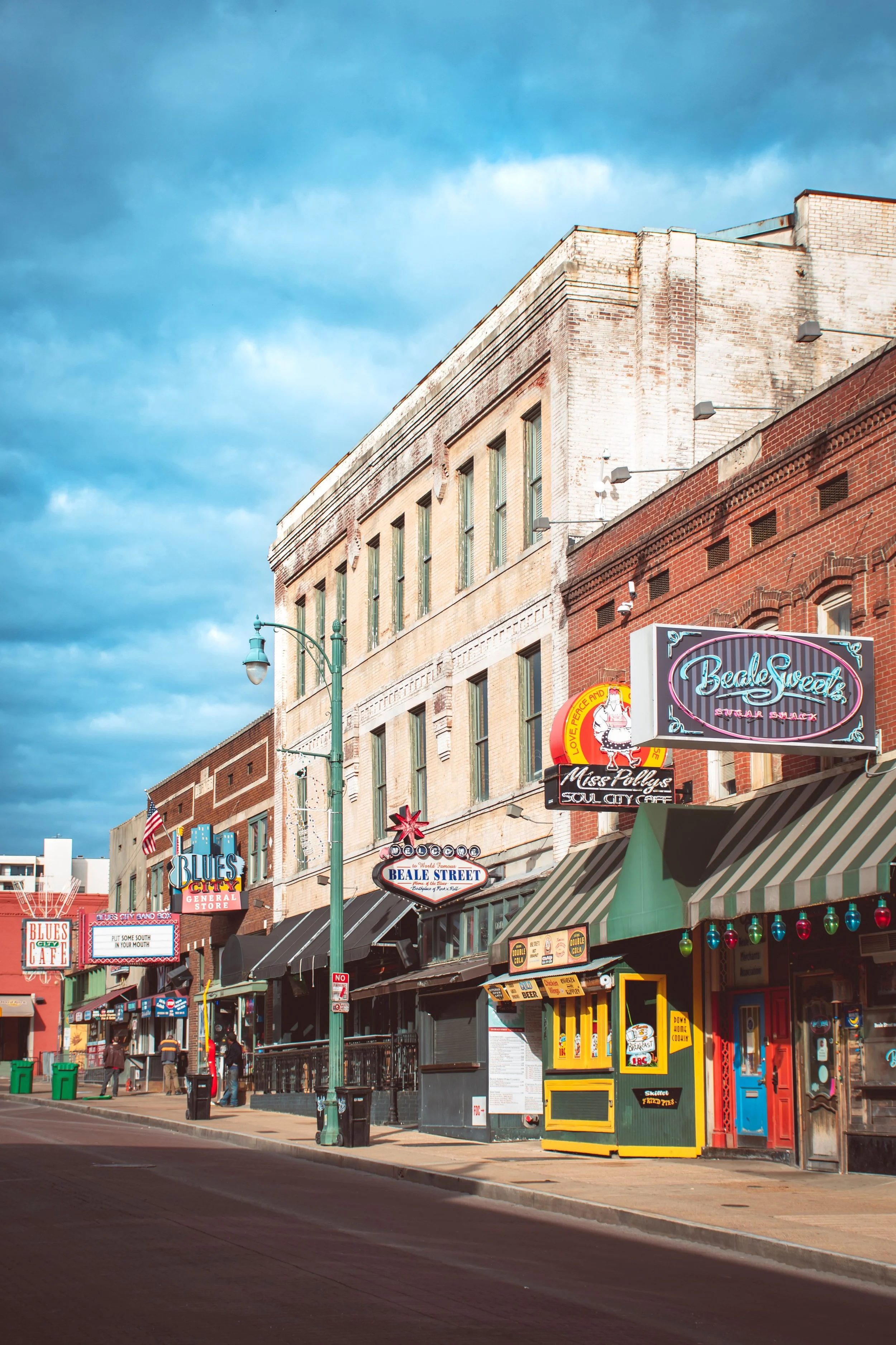 Street scene in Beale Street with colorful storefronts, signs, and a cloudy sky above.