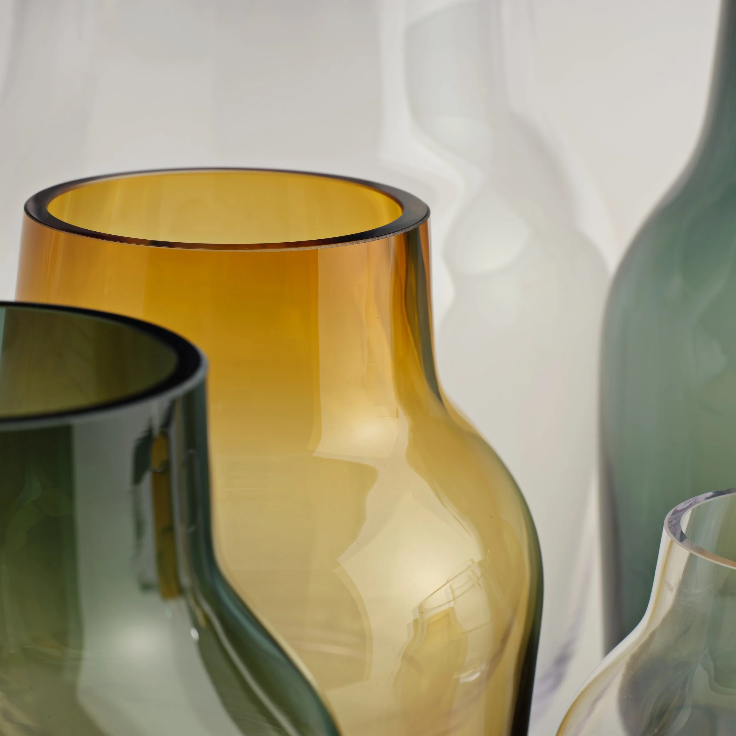 Silent vase for Muuto tegnet av Andreas Engesvik. Nærbilde av en gul vase med svart kant og et lite glass med vann, plassert på en grønn overflate.
