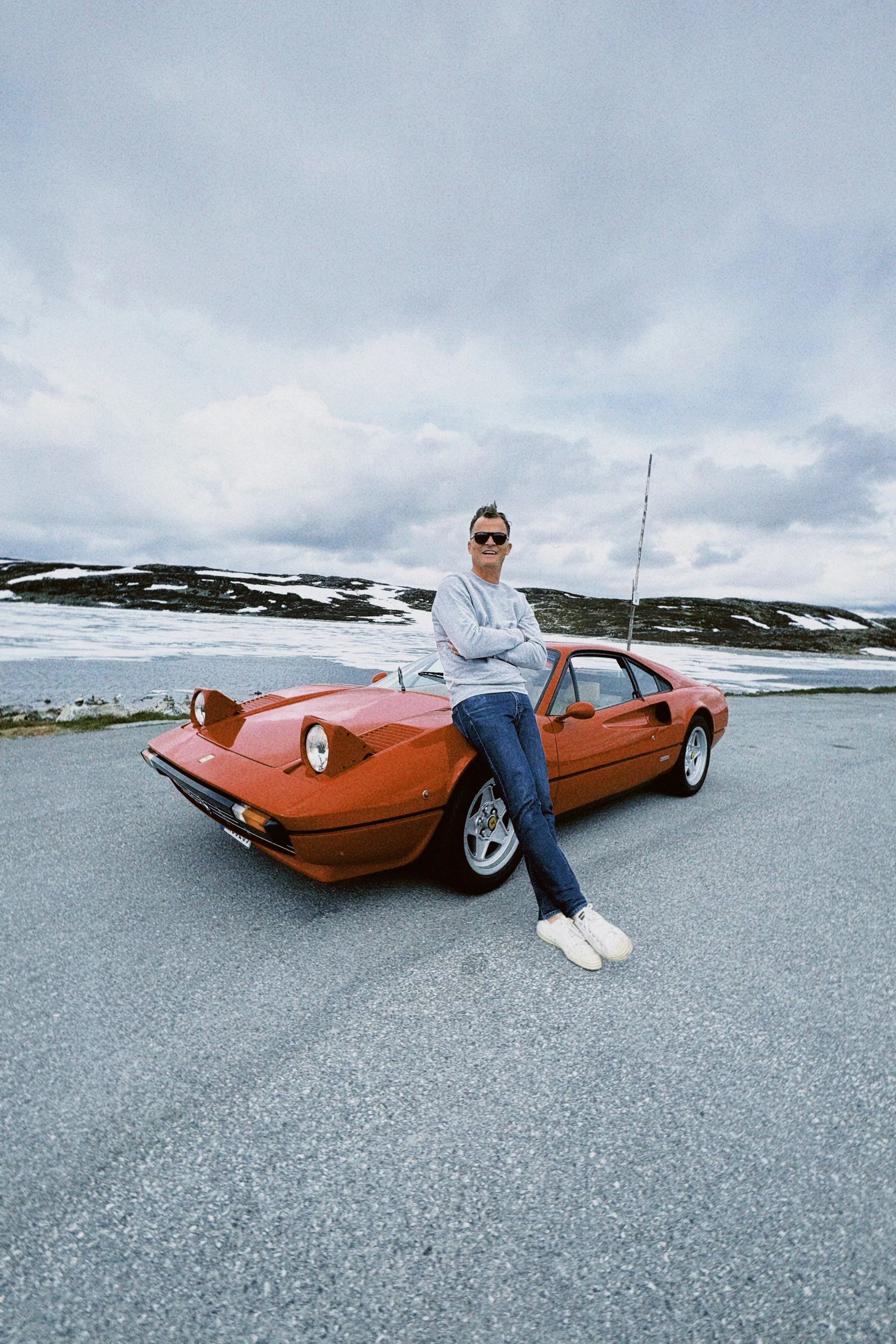 Andreas Engesvik står ved en rød sportsbil  Ferrari