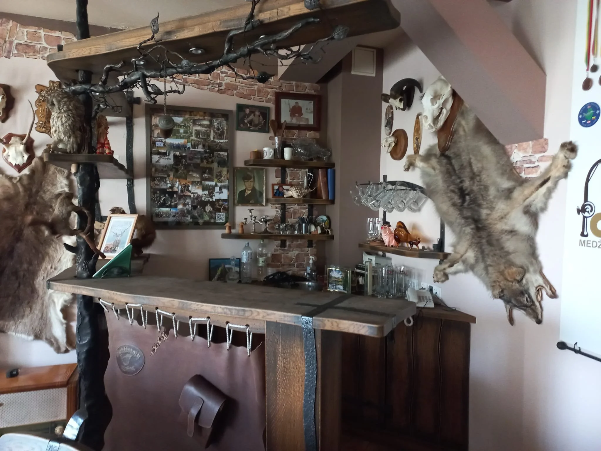 Inredning av ett rustikt sinne med ett träbord, väggdekorationer, fotografier, och olika stylisha skallar och djurhudar, samt en växt.
