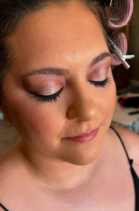 Close-up of a woman with closed eyes, showing shimmery eye makeup, long eyelashes, and smooth skin.