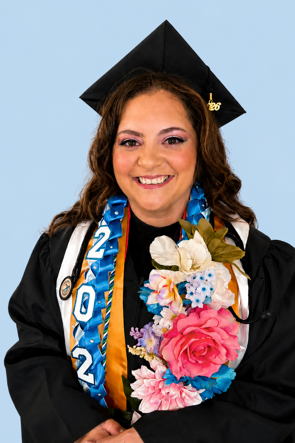 A woman in a graduation cap and gown holding a bouquet of colorful flowers, smiling at the camera.