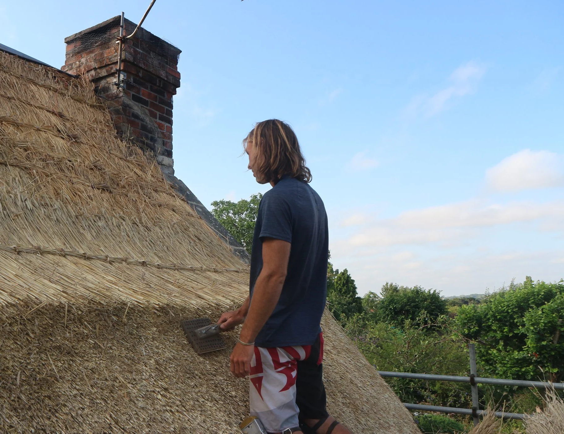 Master thatcher that specializes in wheat straw thatching a roof using his leggett, keeping the craft alive.