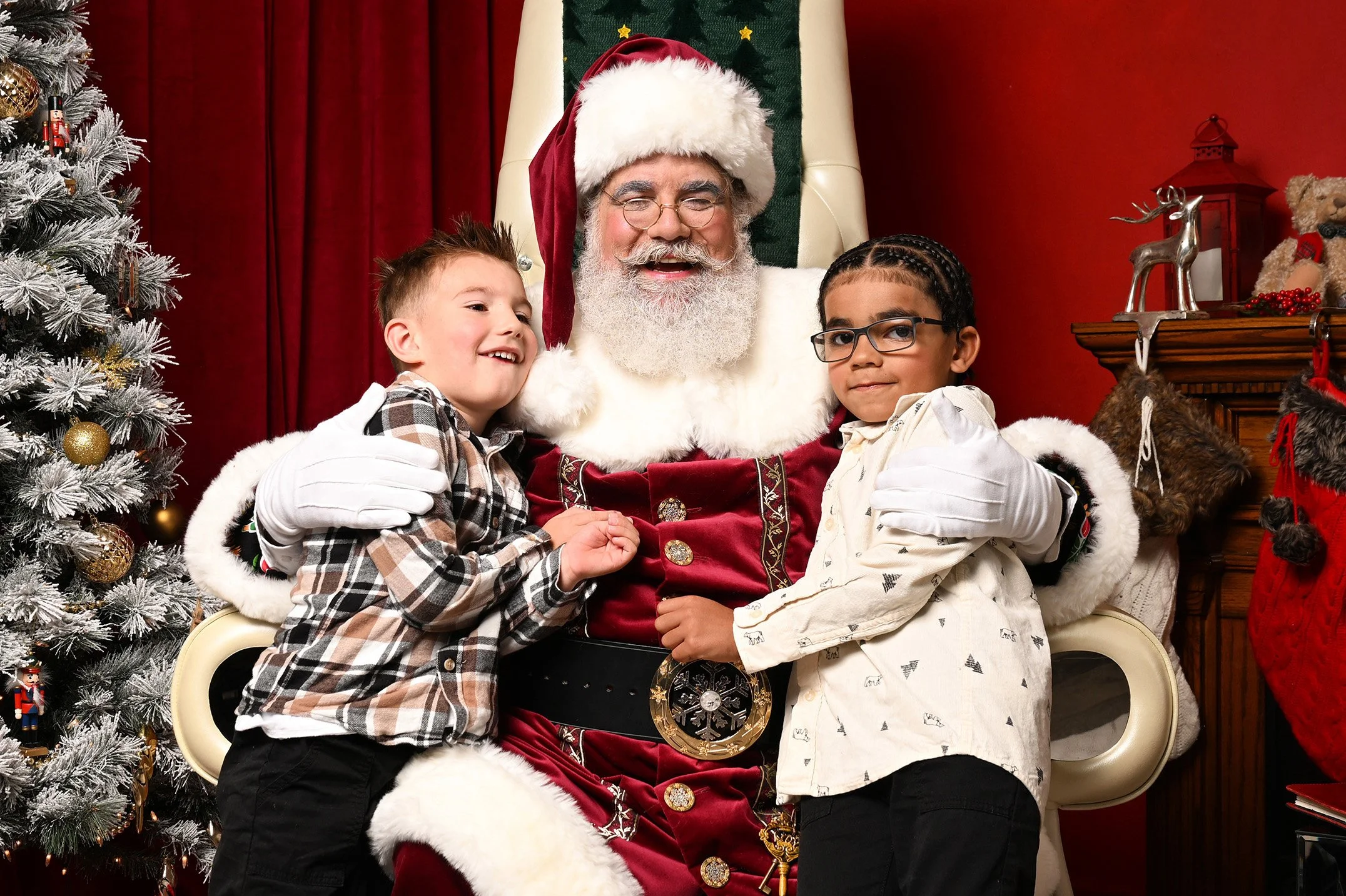 Two boys flank Santa Claus as they all laugh.