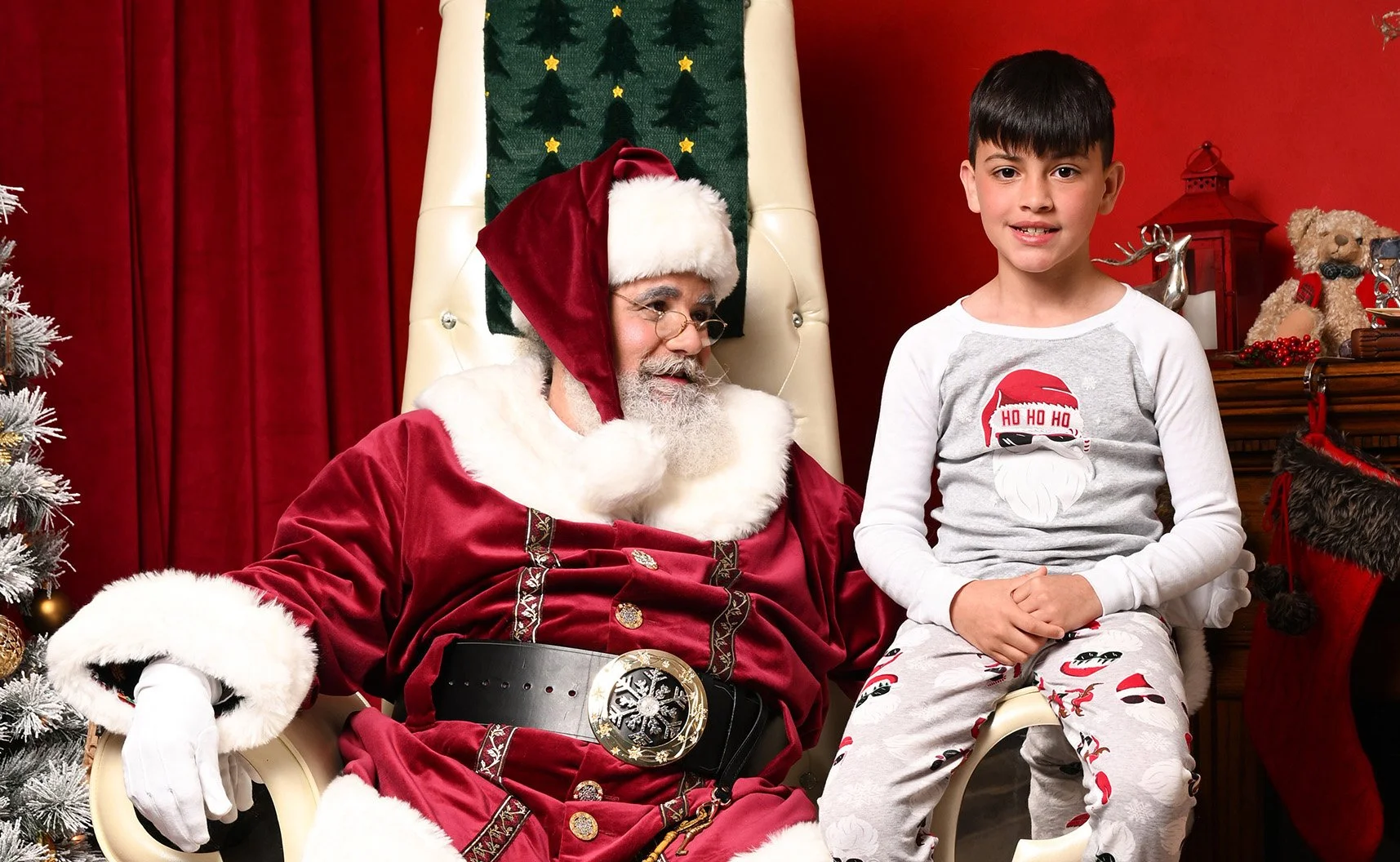 A boy smiles as he sits next to Santa.
