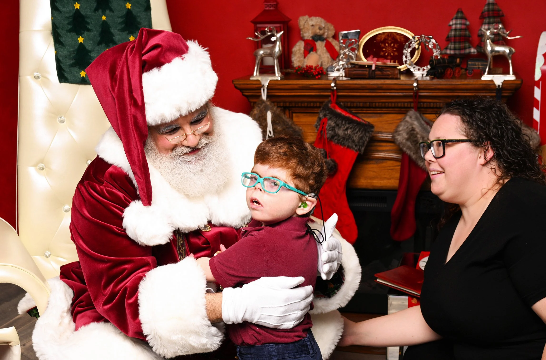 A boy and his mother approach Santa Claus.