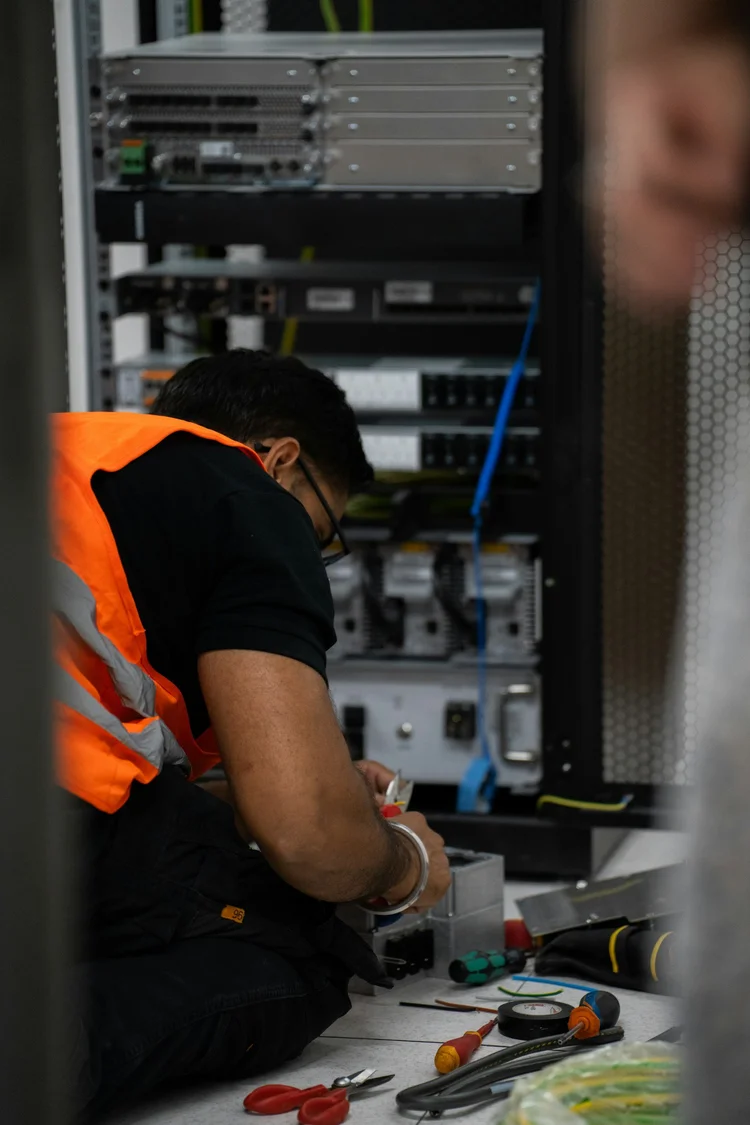 IT technician working on network equipment in a server rack