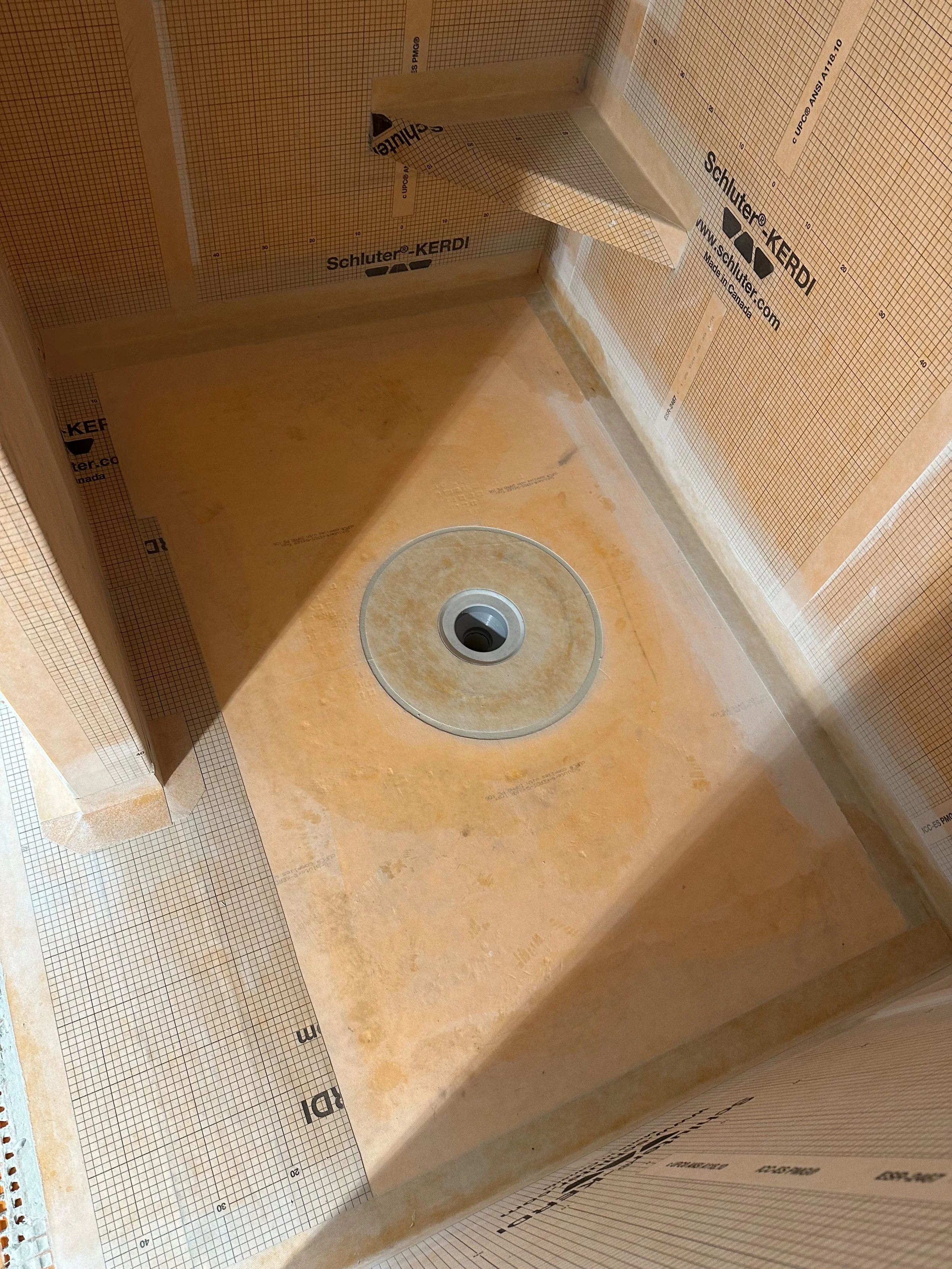 Construction of a bathroom sink with unfinished flooring and blue grid insulation panels on the walls.