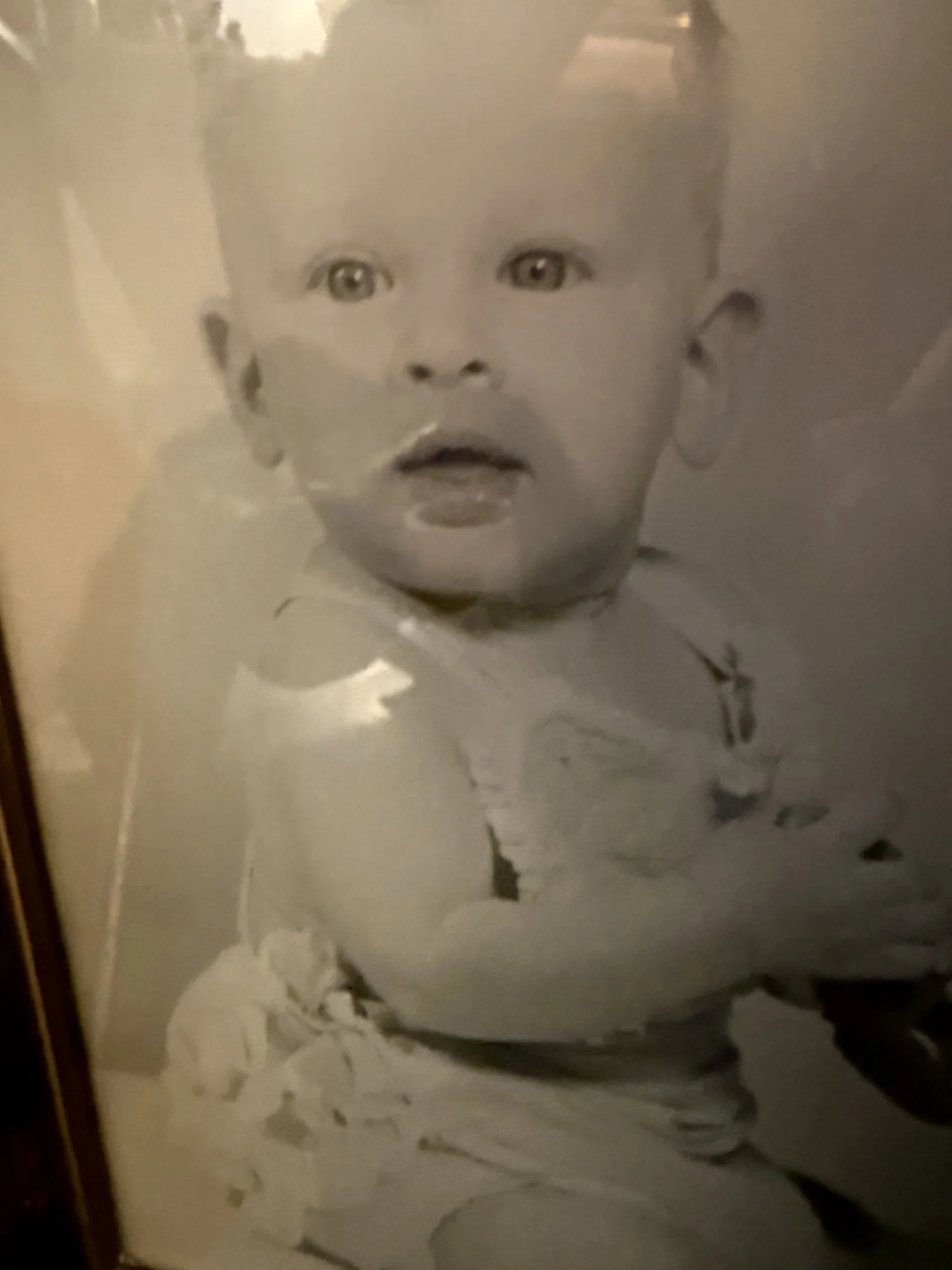 A black and white painting of a young child's face with big eyes and short hair, on a canvas with abstract black and white brushstrokes.
