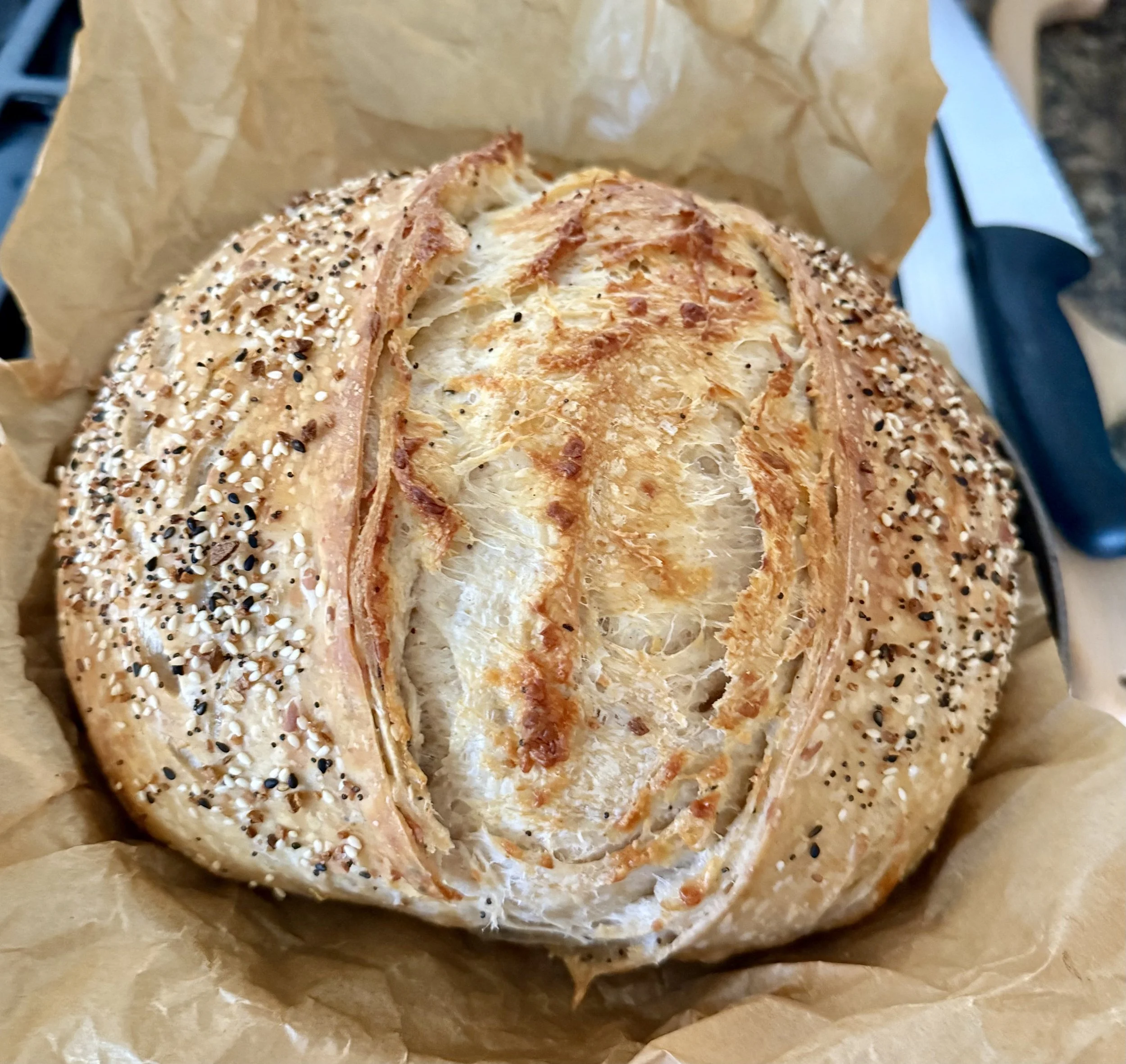 A sliced multigrain bagel with seeds, served on parchment paper.