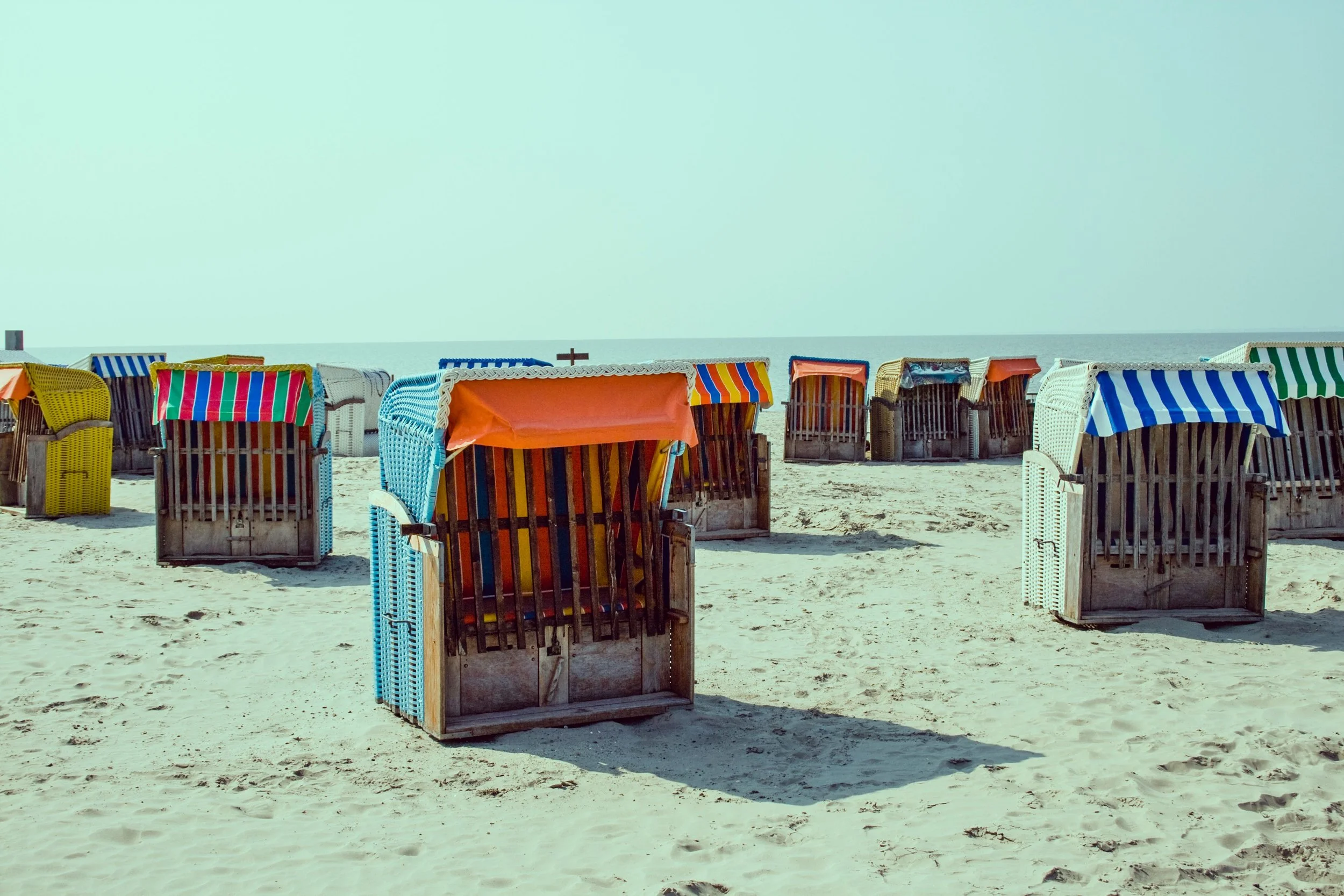 Colourful beach cabanas representing vacation-ready skin after body sugaring and spray tanning at Wyld Sol Calgary.