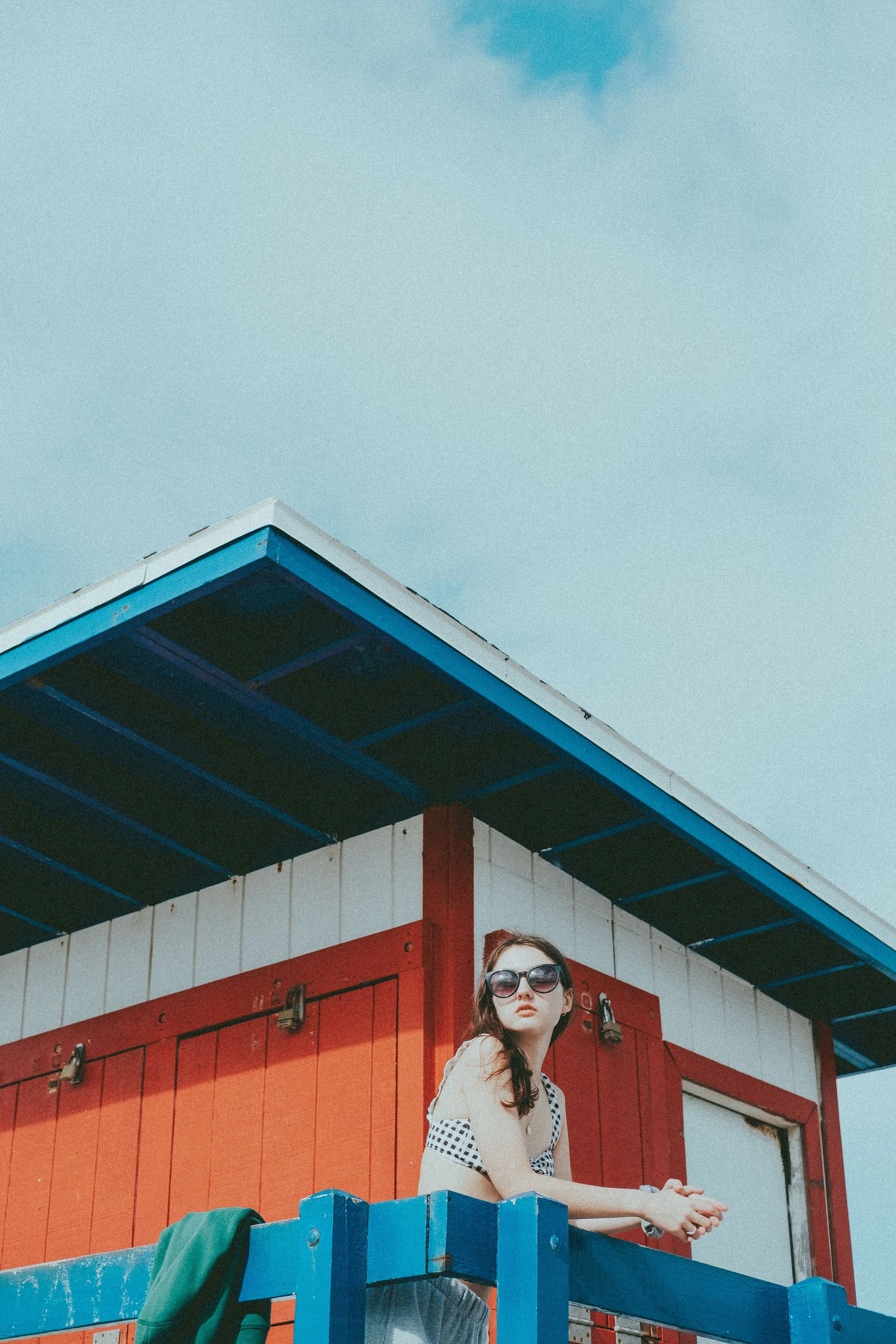 Confident woman wearing sunglasses outside in a retro-inspired setting, representing the relaxed, body-positive atmosphere at Wyld Sol Body Sugaring & Spray Tanning in Calgary.