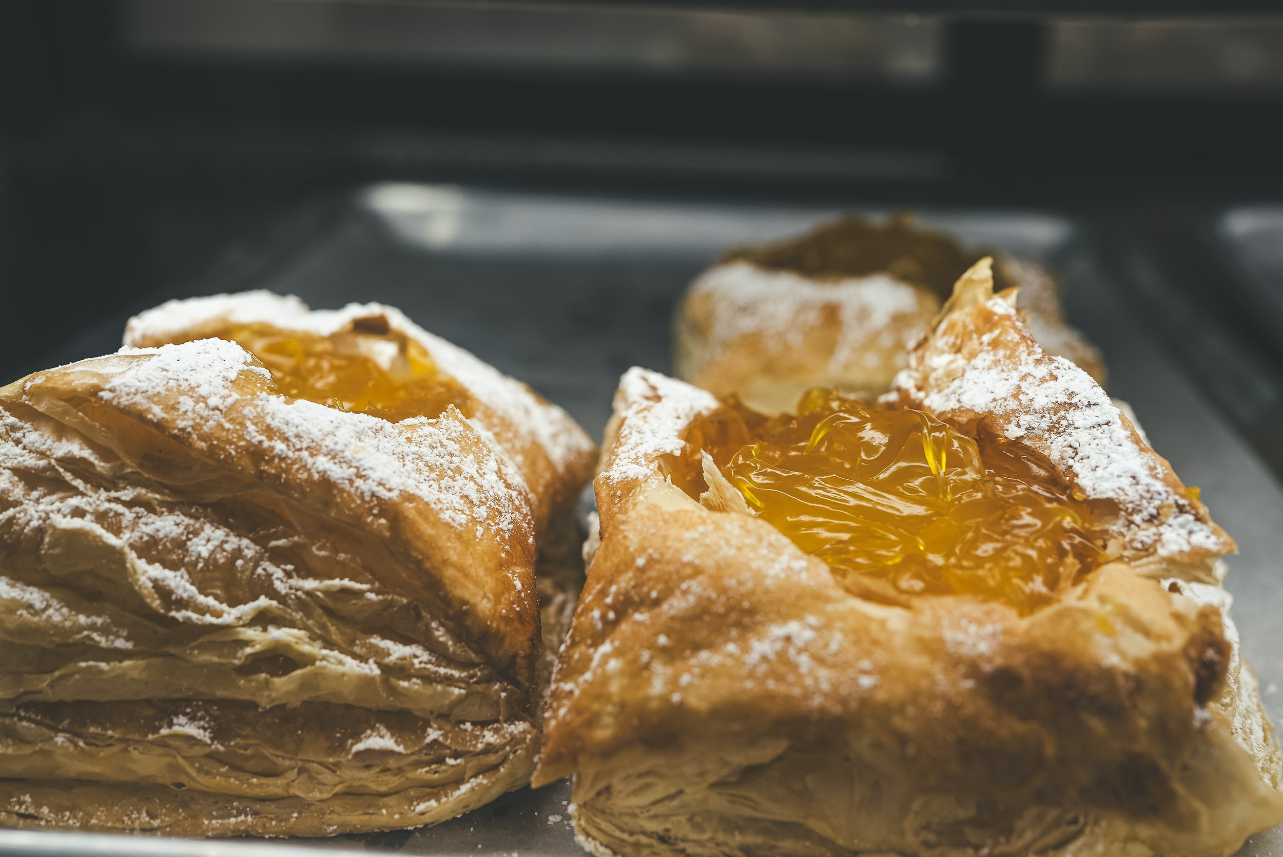 Pastries topped with powdered sugar and filled with orange marmalade in an oven.