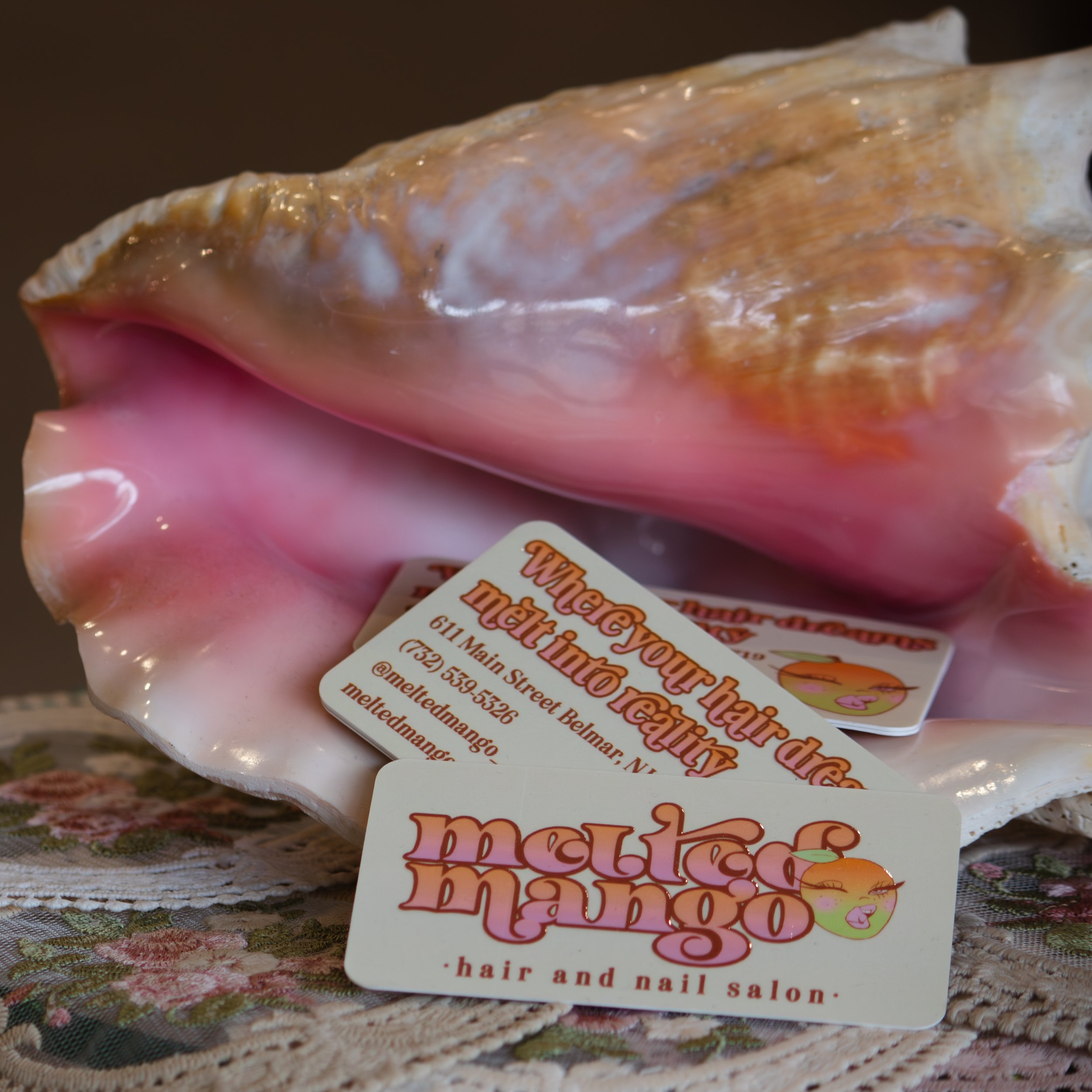 Close-up of hair salon business cards with colorful text and illustrations, resting on a textured tablecloth.