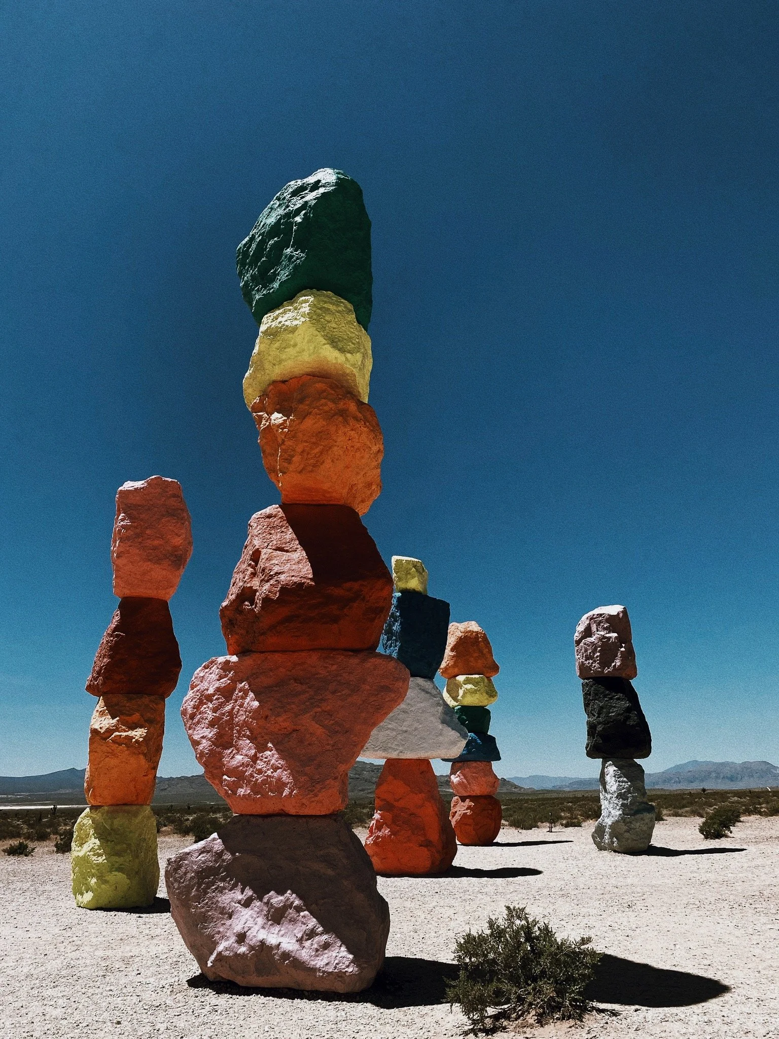 Colorful stacked rocks in a desert landscape with a clear blue sky.