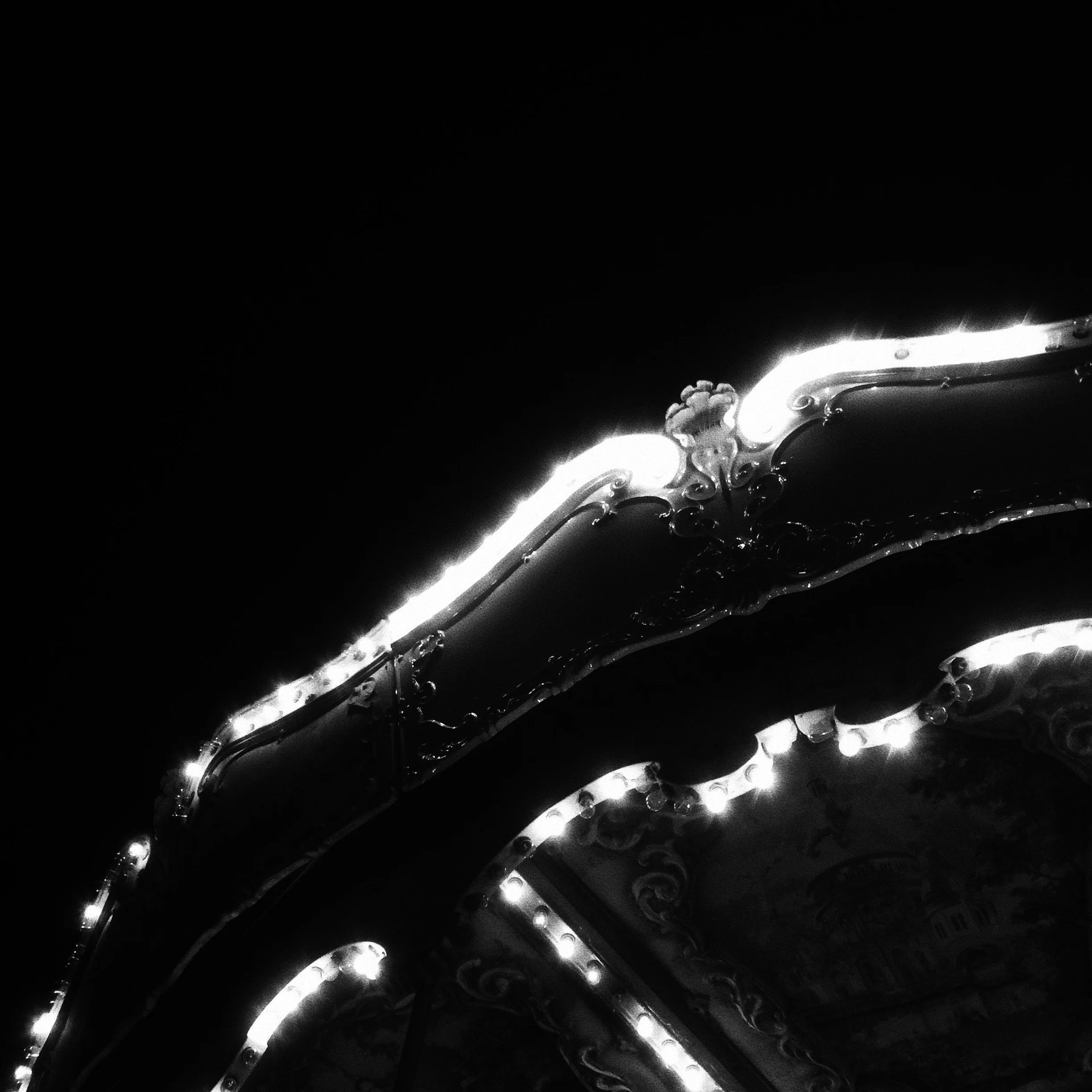 Close-up view of a metallic bicycle chain with reflections on its surface, set against a dark background.