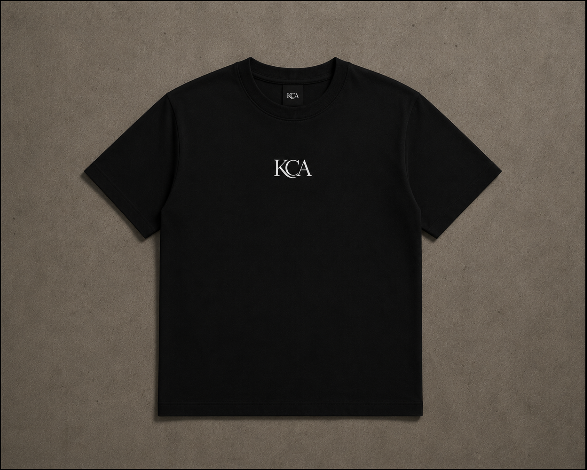Black T-shirt with white 'KCA' logo in the center, laid flat on a neutral background.