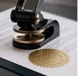 A gold embossed seal pressing onto a document.