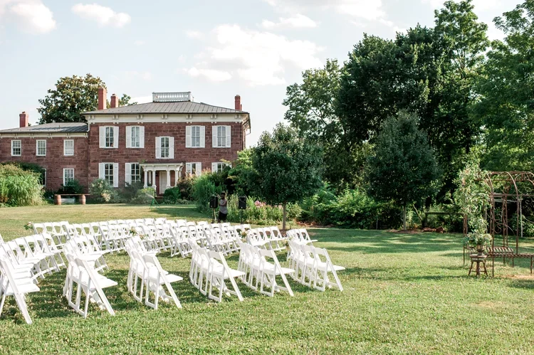 Outdoor wedding ceremony setup in front of a large brick mansion at Rocklands Farm Winery