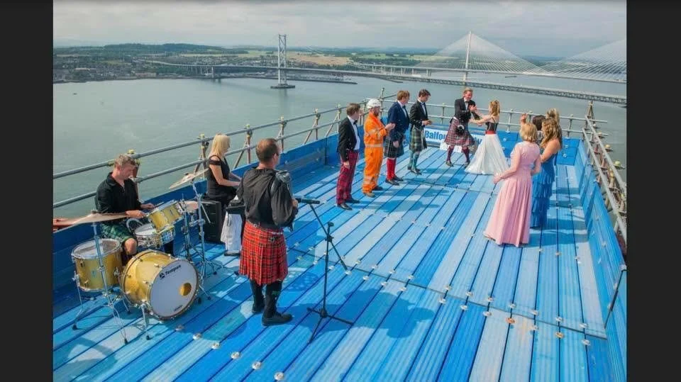 People having a wedding ceremony on a rooftop with a band playing nearby, overlooking a river and modern bridges in the background.  Clappy Doo Ceilidh band Scottish Ceilidh band Scottish music