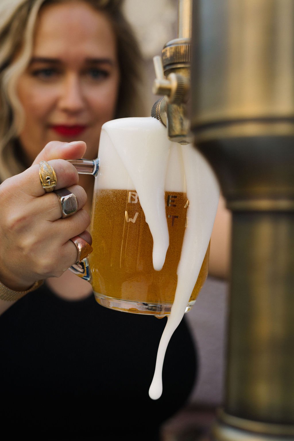 Alexa from Bread Water Beer Company pouring a foamy beer from a tap into a glass mug.