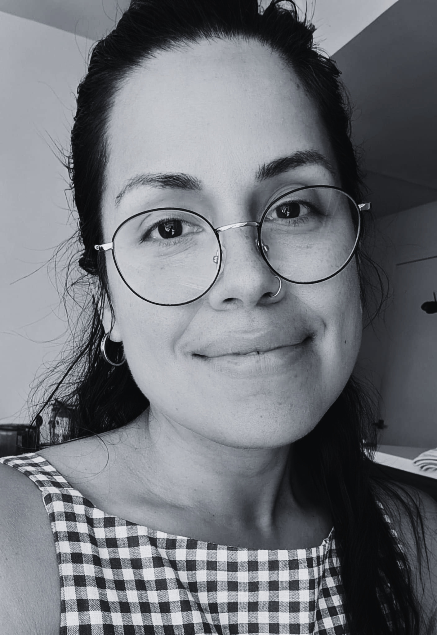 Black-and-white selfie portrait of Fiorella Campodonico, author of this project, smiling genuinely at the camera with a softly blurred background.