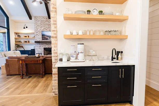 Kitchen area with a black cabinet and open wooden shelves holding dishes and decor.