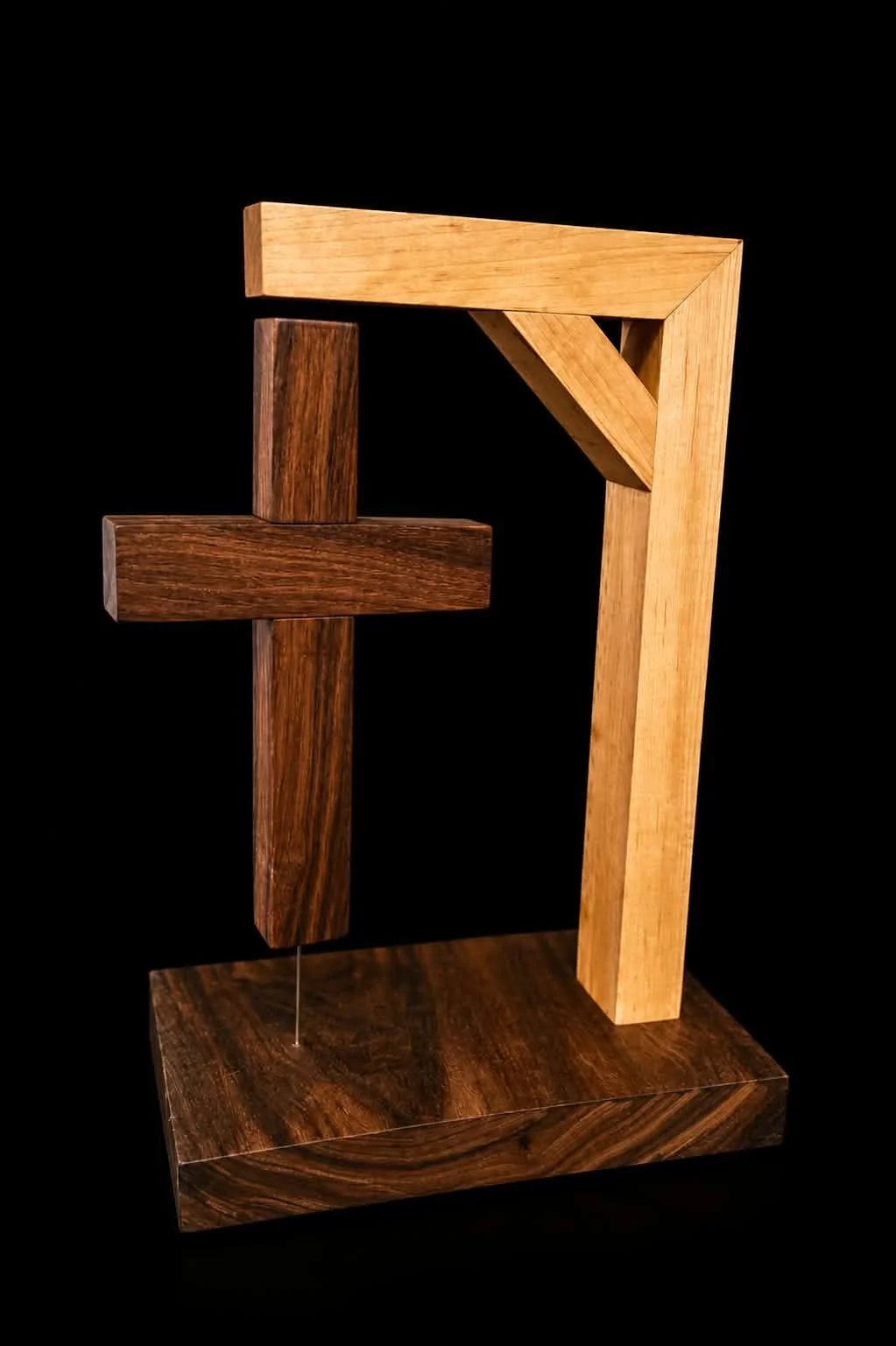 Abstract sculpture made of geometric wooden blocks with different shades of brown, mounted on a wooden base against a black background.