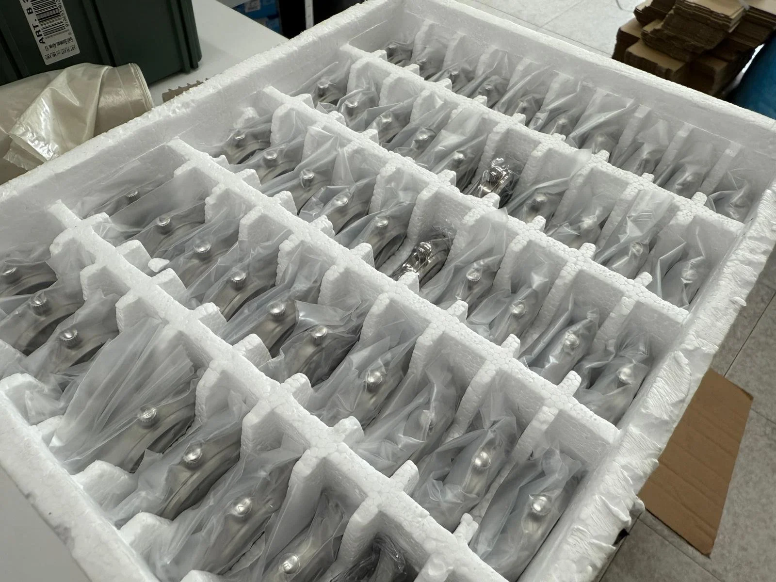 L'articolo mostra un pacco di coltelli da cucina con manici in acciaio, ancora imballati in bustine di plastica e sistemati in un contenitore di polistirolo.