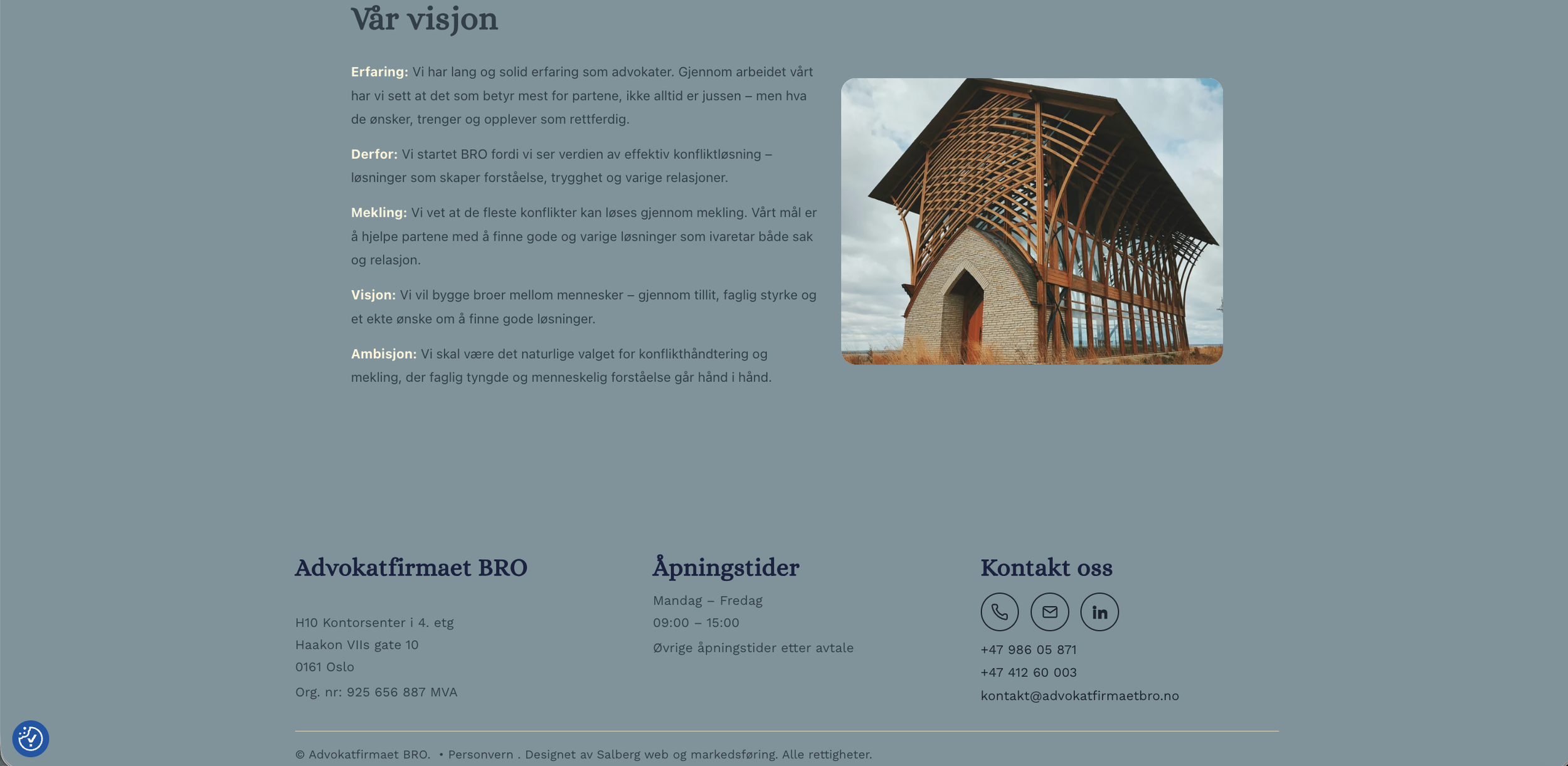 Et bilde av en bygning under konstruksjon med en trestruktur og en steinbue i fronten, sett mot en himmel med skyer.