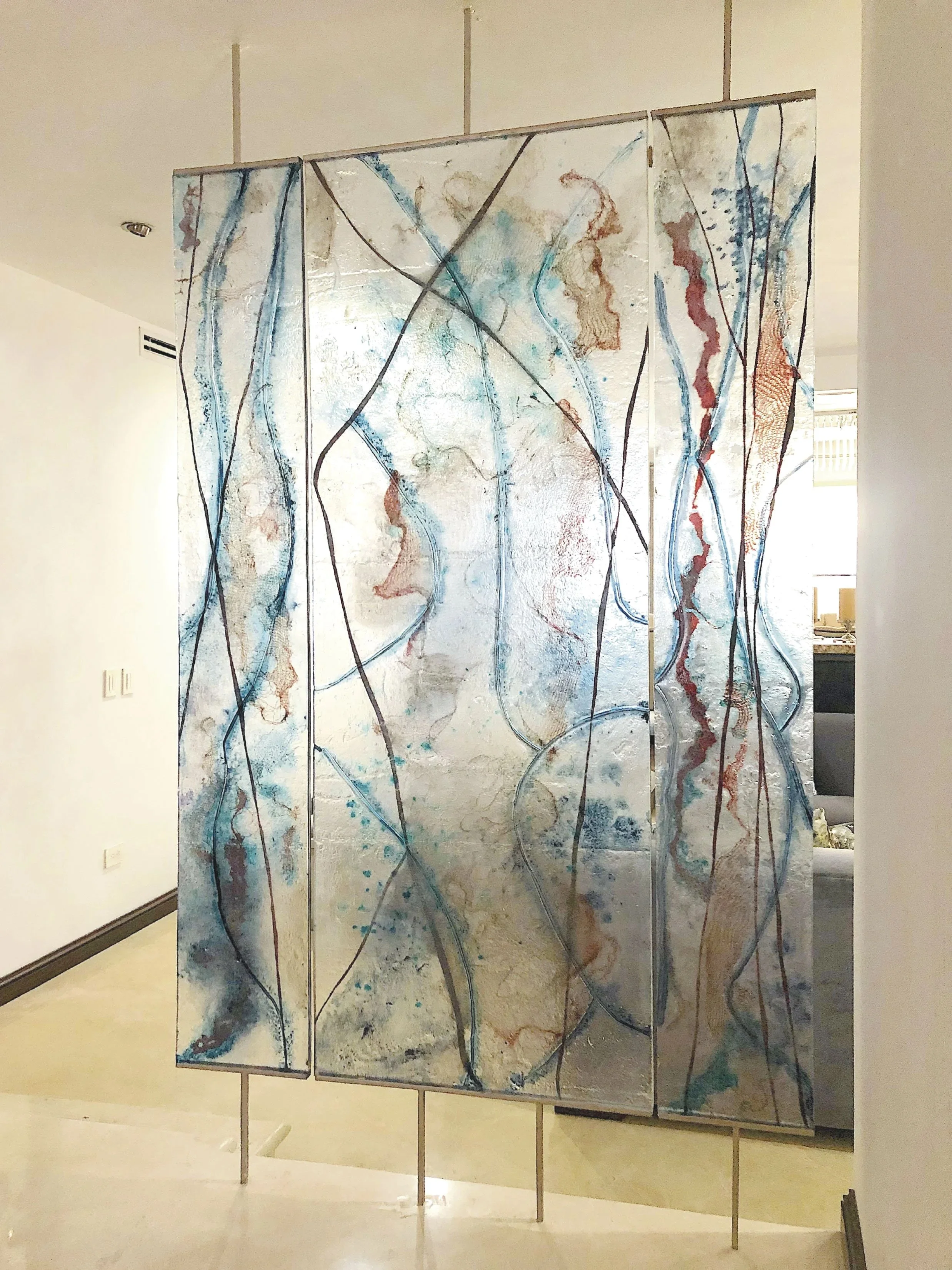 
Description: An architectural glass triptych designed as a space divider for a residential entrance hall. Inspired by the delicate texture of fabric, the textured panels act as a translucent threshold, capturing light like fluid drawings to alter sp