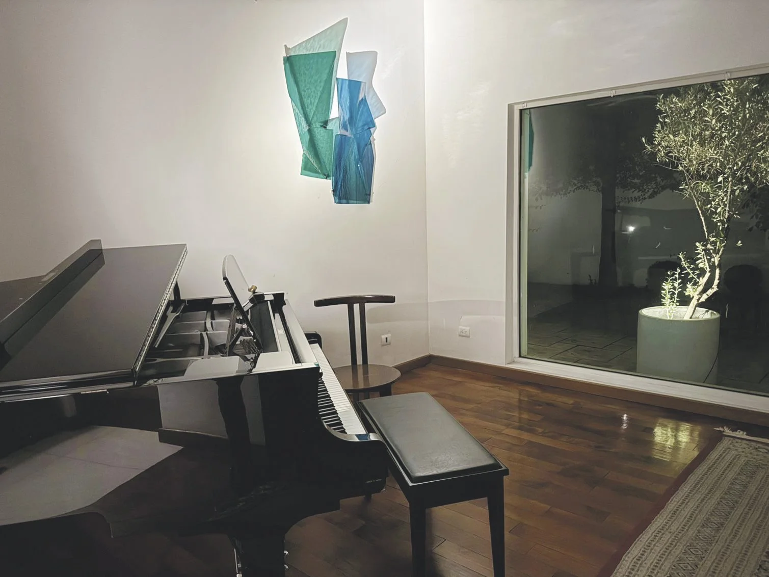 A work that transforms dynamically from day to night. While daylight illuminates the folds, artificial evening light projects colored shadows onto the wall.
