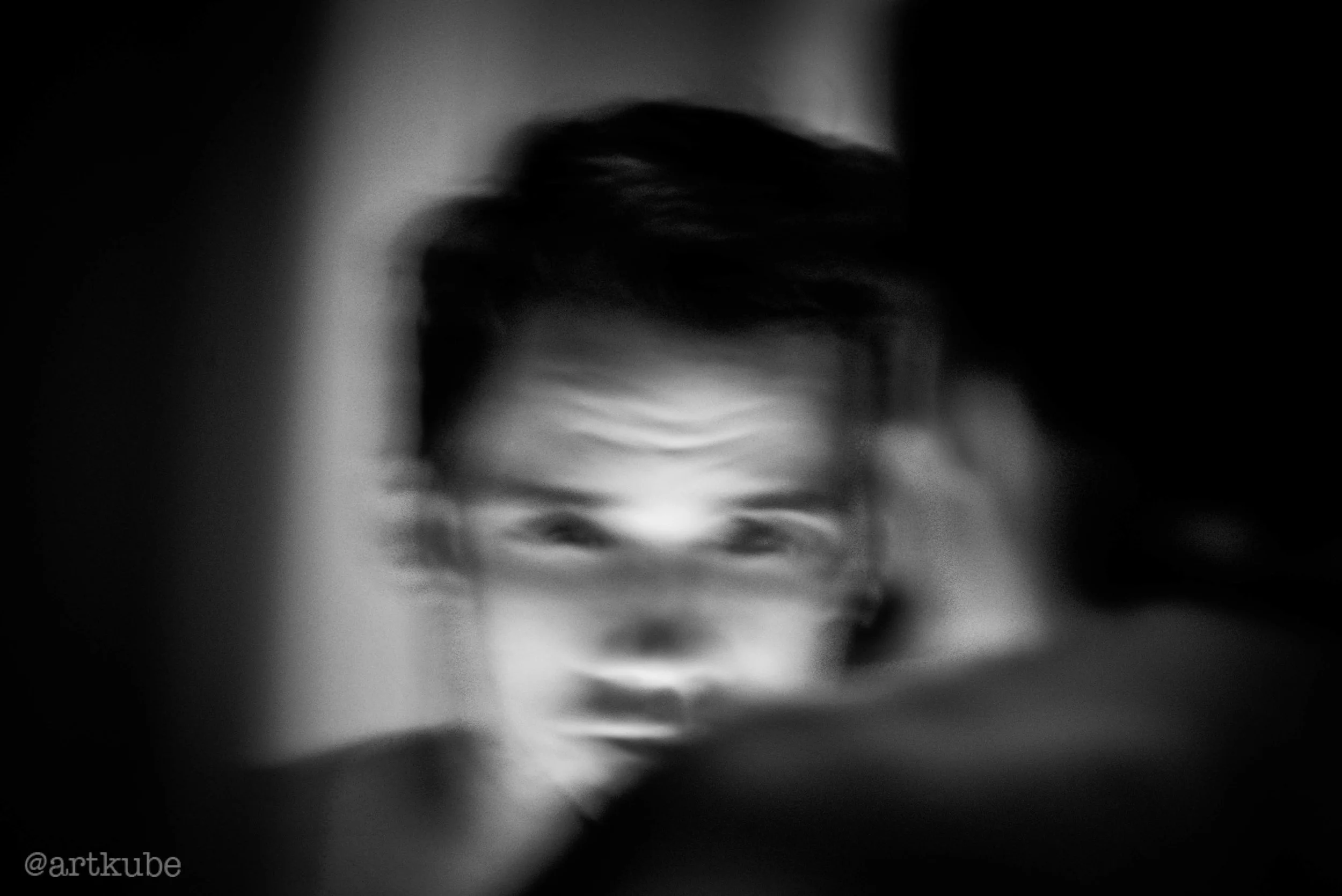 A black and white abstract image of a face with distorted features, captured in a surreal and painterly style.