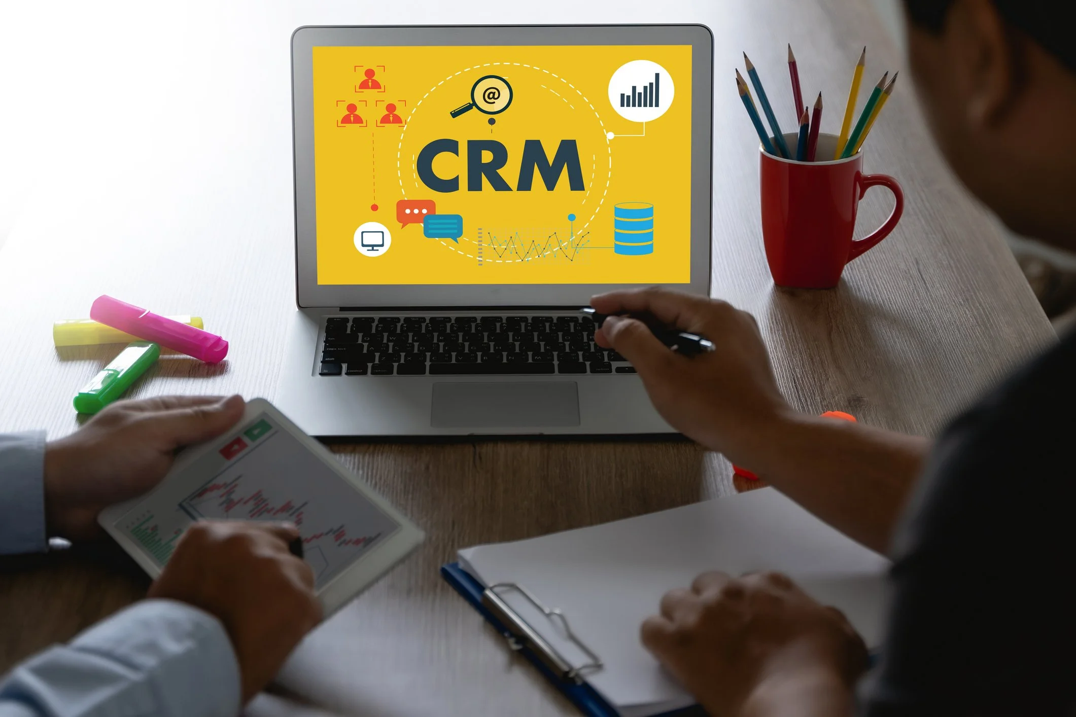 Two people working together beside a laptop displaying a CRM dashboard.